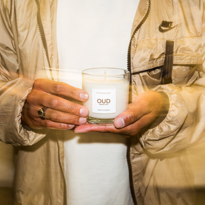 Person holding a candle labeled 'OUD' in a neutral setting