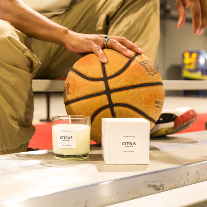 Person holding a basketball with a candle labeled 'Citrus' on a table.